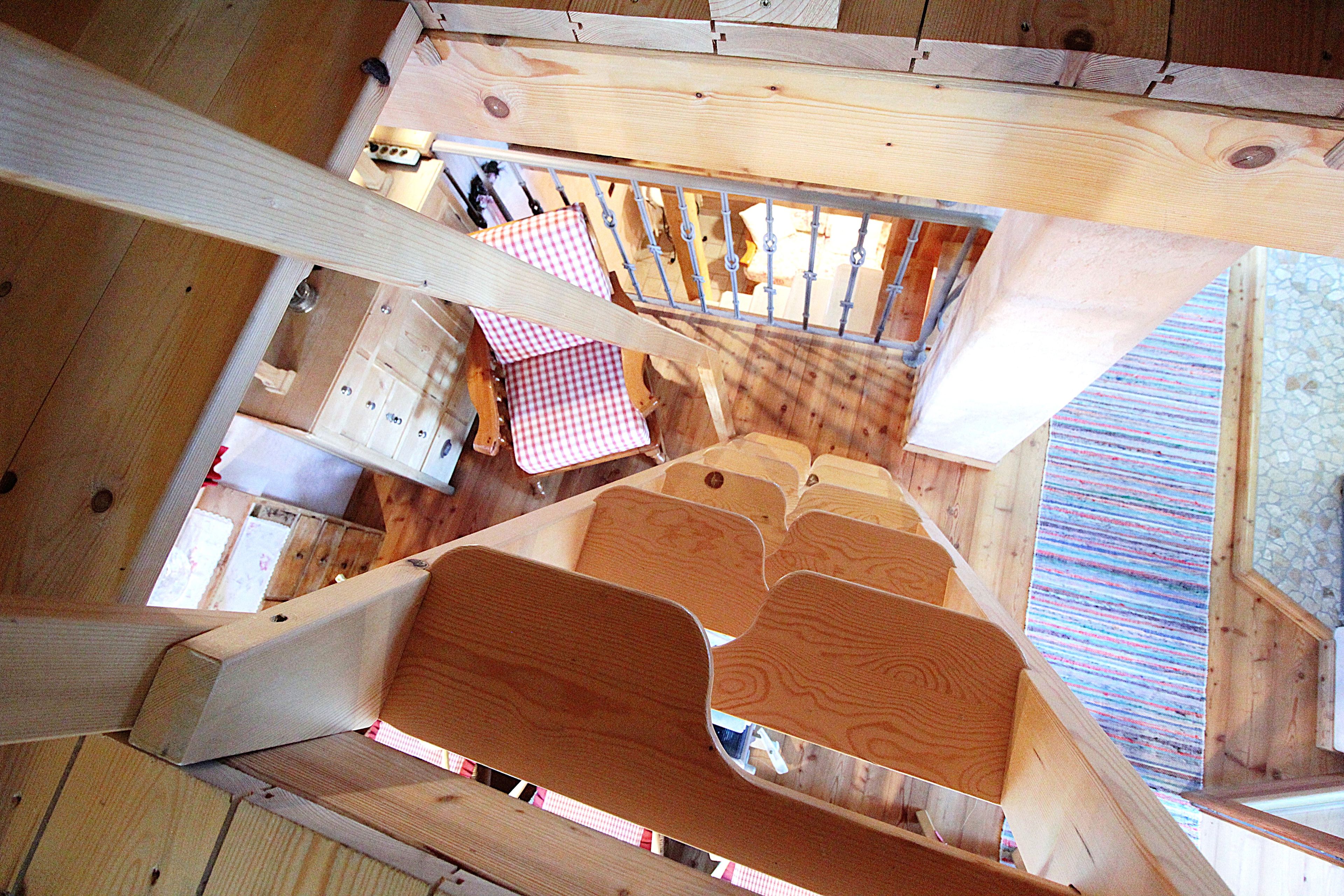 Interior de madera con escalera, zona de estar y mantel a cuadros.