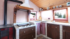 A kitchen with wooden cabinets, a stove, and a window with a view of trees.