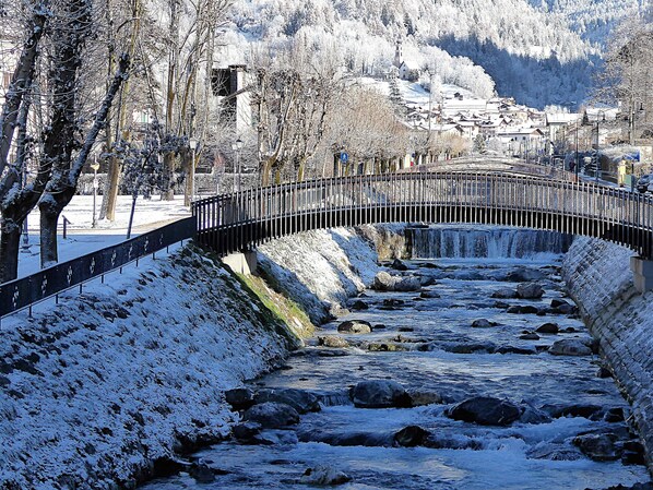 Un puente cubierto de nieve sobre un río, con un pueblo al fondo.