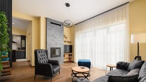 Un salon moderne avec une cheminée, un canapé, une table basse et un téléviseur.
