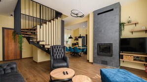 Un salon moderne avec un escalier, une cheminée et un coin repas.