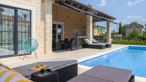 Un espace aménagé au bord de la piscine, avec des chaises longues, une table et une chaise.