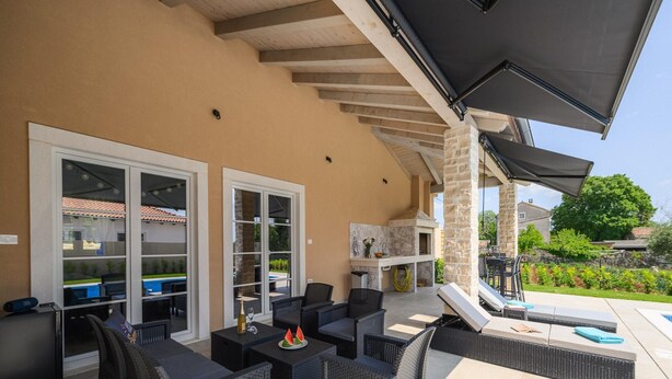 Une terrasse extérieure aménagée avec des meubles en osier, un barbecue et une piscine.
