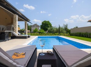Une piscine avec des chaises longues et un verre de gin.