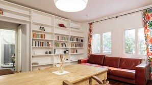 A cozy living room with a wooden table, red leather sofa, and a bookshelf filled with books. - Elegant apartment in Trastevere- Bolognese 45 (Rome)