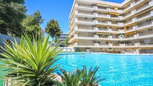 Ein mehrstöckiges Hotel mit Schwimmbad, umgeben von viel Grün.