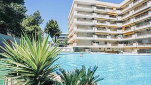 A multi-story hotel with a swimming pool, balconies, and a clear sky. - Salou Luxe Stay | Chill-out | Cozy ( 2BR ) Parking (Salou)