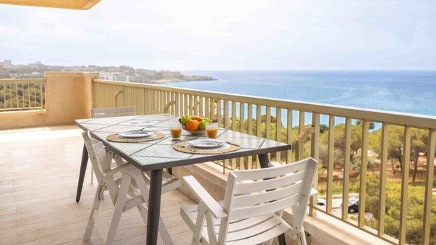 A balcony with a table set for two, overlooking a coastal view. - Salou Luxe Stay | Chill-out | Cozy ( 2BR ) Parking (Salou)