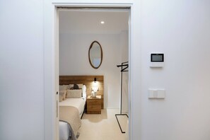 Habitación de hotel con cama, mesita de noche, lámpara y termostato en la pared.
