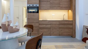 A modern kitchen with wooden cabinetry, a glass dining table, and a built-in oven.