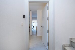 Un pasillo estrecho con una puerta que da a una habitación con una silla y una mesa.