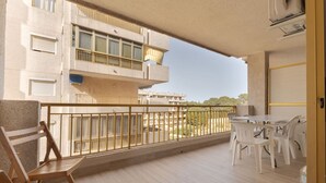 En balkon med et bord, stole og gelænder, samt udsigt til andre bygninger.