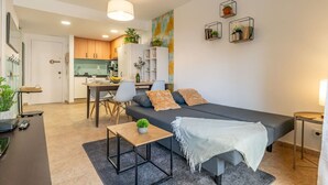 Un salon moderne avec un canapé, une table à manger et un coin cuisine à l’arrière-plan.