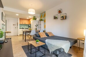 Una sala moderna con un sofá, una mesa de comedor y una zona de cocina al fondo.