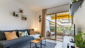 Un salon moderne avec un canapé, une table basse et un balcon aménagé avec des sièges d’extérieur.