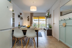 A modern kitchen with a dining area, a large window with a yellow curtain, and a view of a building. - Honolulu (6pax) Cozy | Warm | Wifi | Parking | Parking (Salou)