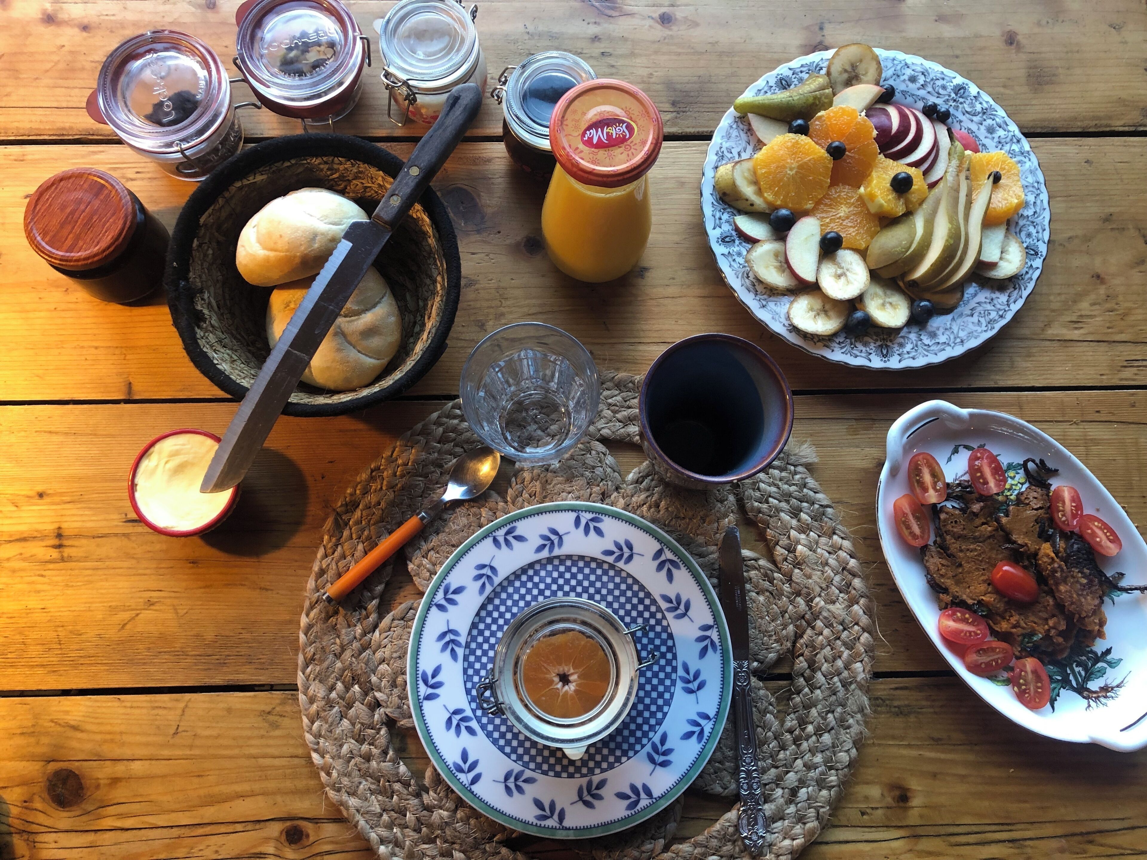 Una mesa de madera con diversos alimentos, como pan, fruta y salsas.