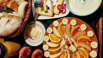 A variety of food items including bread, cheese, fruits, and a bowl of yogurt.