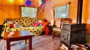 Un interior acogedor con un sofá estampado, una mesa de madera y una estufa antigua.