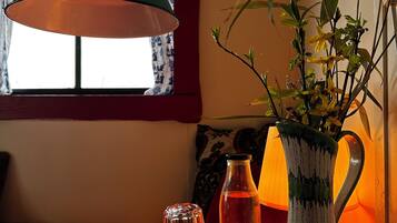Een tafel met een groene lamp, een vaas met gele bloemen en een glazen fles.