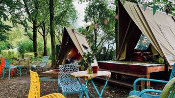 A campsite with two tents, a table, and colorful chairs.