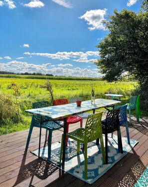 An outdoor dining area with a table and chairs, surrounded by a lush green field and a clear blue sky. - Camping De Helleborus (Groningen)