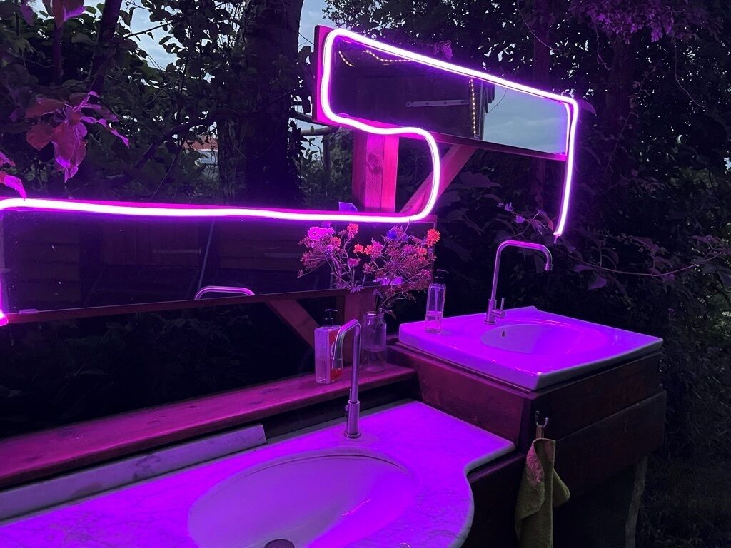 Un baño con diseño moderno, que incluye un espejo grande, un lavamanos y un mueble para lavabo.