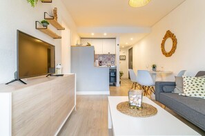 A modern living room with a TV, sofa, and dining area.
