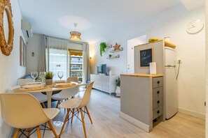 Cocina compacta con comedor, refrigerador, reloj y ventana con cortinas.