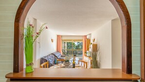 Un comedor con mesa de madera, sillas, un sofá y vistas a través de un arco.
