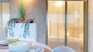 A dining area with a table set for two, a textured wall, and a window with a view. - Salou | Modern | Cozy (5pax) Wifi | AA|Parking (Salou)