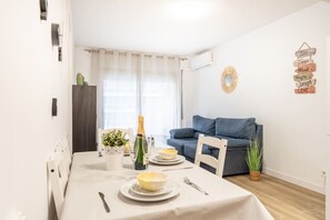 A dining area with a table set for two, a bottle of champagne, and a blue sofa in the background.