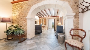 A stone-walled hallway with a wooden chair and a potted plant. - Can Jaume Fuster in Buger (Buger)
