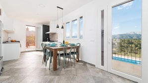 A modern kitchen with a dining area, large windows, and a view of mountains. - Can Jaume Fuster in Buger (Buger)