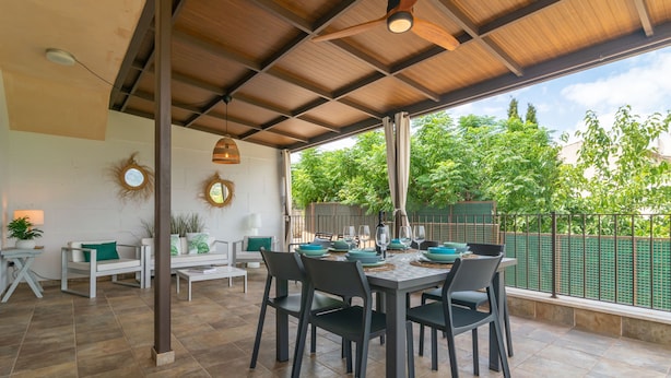 A covered patio with a dining table set for six, surrounded by chairs. - Can Jaume Fuster in Buger (Buger)