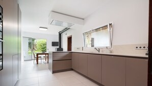 A modern kitchen with a large island, built-in appliances, and a view of greenery through the window. - Son Jordi in Mallorca (Son Servera)