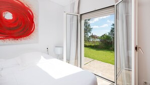 A bedroom with a large bed, a sliding glass door leading to a garden, and a red abstract painting on the wall. - Son Jordi in Mallorca (Son Servera)