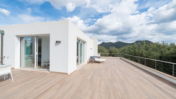 A modern building with a wooden deck, glass sliding doors, and a view of mountains. - Son Jordi in Mallorca (Son Servera)