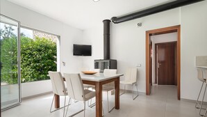 A modern dining area with a large table and chairs, a built-in stove, and a television on the wall. - Son Jordi in Mallorca (Son Servera)