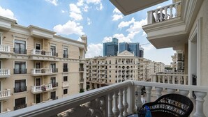 A balcony with ornate balustrades overlooking a cityscape with historic buildings and modern skyscrapers. - Tashkent city Bulevard Fontaine (Tashkent)