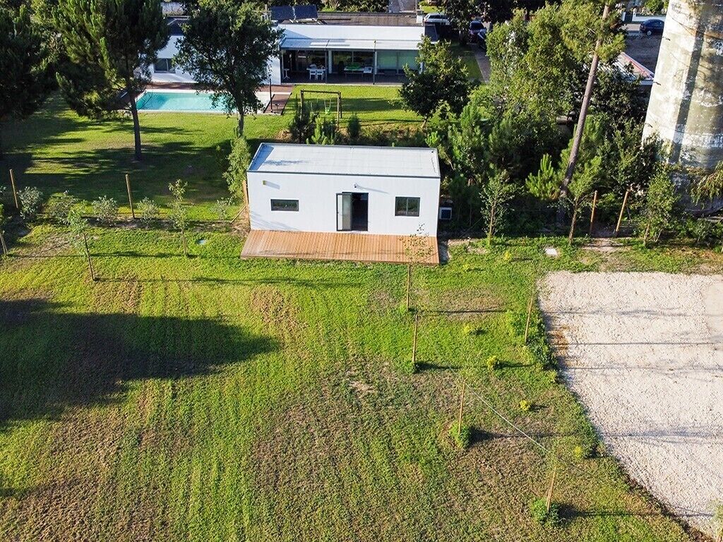 Een modern, gelijkvloers huis met een klein terras, omgeven door een verzorgd gazon en bomen.