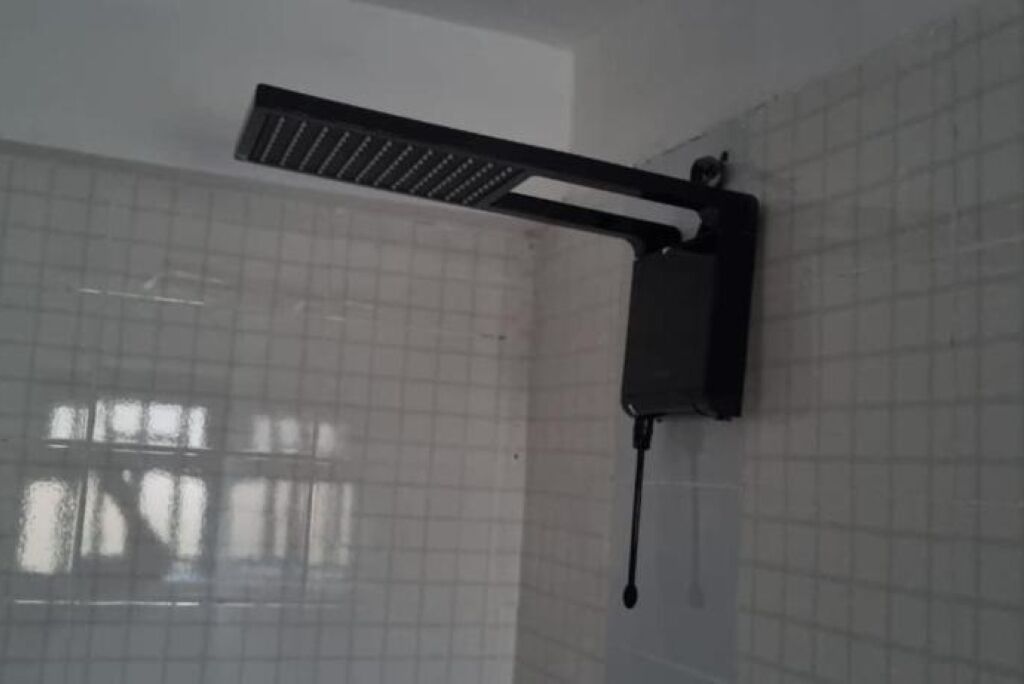 A tiled wall with a mounted showerhead.