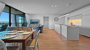 A modern kitchen with a central island, a dining area with a view, and a large window overlooking a landscape.