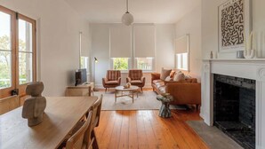 A spacious living room with a fireplace, wooden flooring, and a large window.