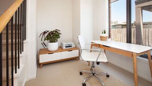 Et moderne kontor med skrivebord, stol, printer og en potteplante.