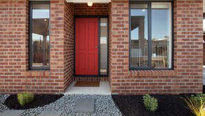 A modern building with a red door, brick walls, and large windows. - Northside Townhouse, Geelong (Norlane)
