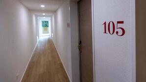 En gang med trægulv, hvide vægge og en dør med nummer 105.