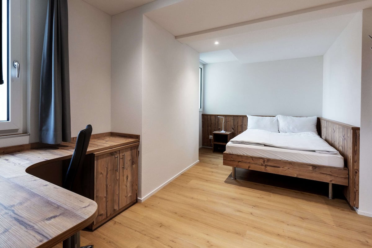 A bedroom with a wooden bed, a desk, and a chair.