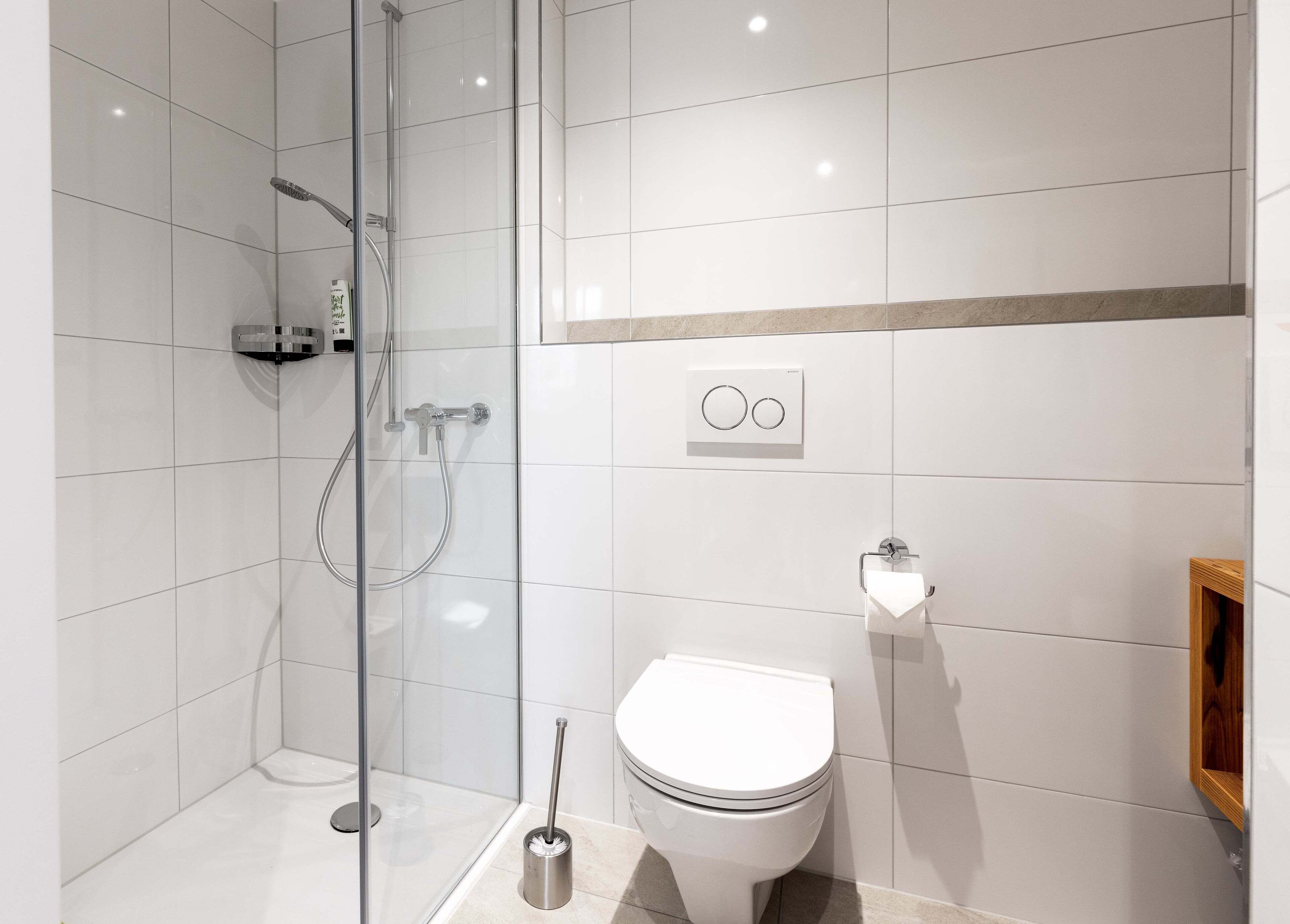 A modern bathroom with a glass-enclosed shower, a toilet, and a bidet.