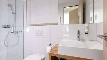 A modern bathroom with a glass-enclosed shower, a white sink, and a mirror above the sink.